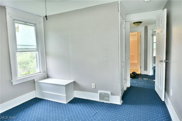 hall with carpet floors, visible vents, and baseboards