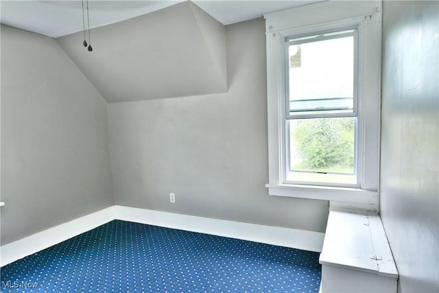 additional living space featuring lofted ceiling, carpet flooring, plenty of natural light, and baseboards