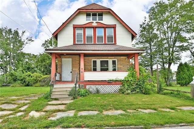 view of front of house with stone siding, a porch, and a front lawn