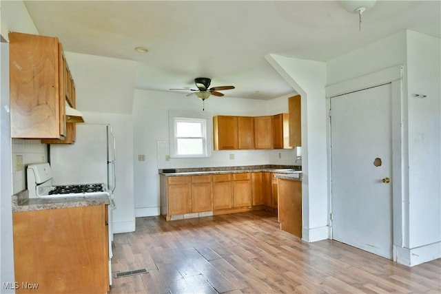 kitchen featuring white appliances, visible vents, brown cabinetry, a ceiling fan, and light wood-style flooring