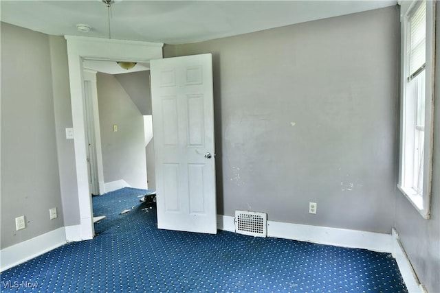 unfurnished bedroom with dark carpet, visible vents, and baseboards