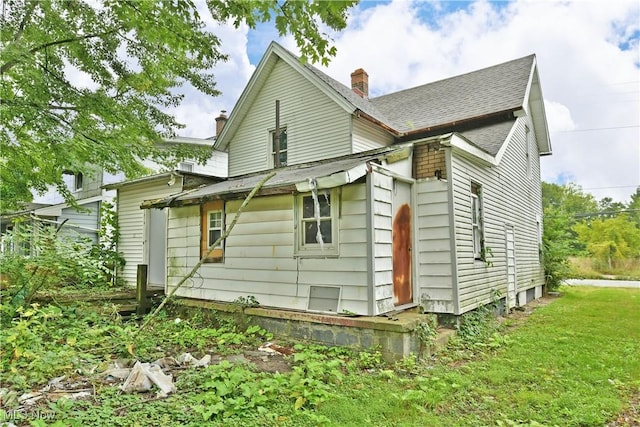 exterior space featuring a yard, a chimney, and roof with shingles