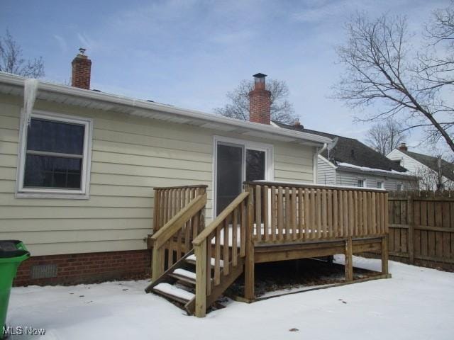 snow covered property featuring crawl space, a chimney, fence, and a deck