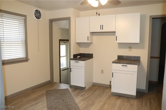 kitchen featuring light wood finished floors, dark countertops, and white cabinets