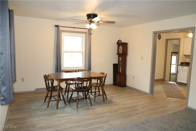 dining area featuring light wood-type flooring, a ceiling fan, and baseboards