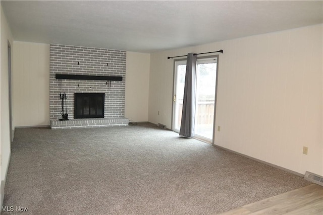 unfurnished living room with carpet floors, visible vents, a fireplace, and baseboards