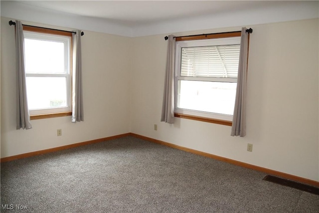 spare room featuring baseboards, visible vents, and carpet flooring