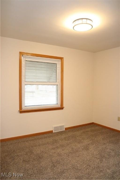 empty room featuring carpet floors, visible vents, and baseboards