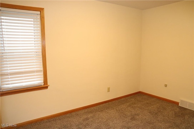 empty room with carpet, visible vents, and baseboards