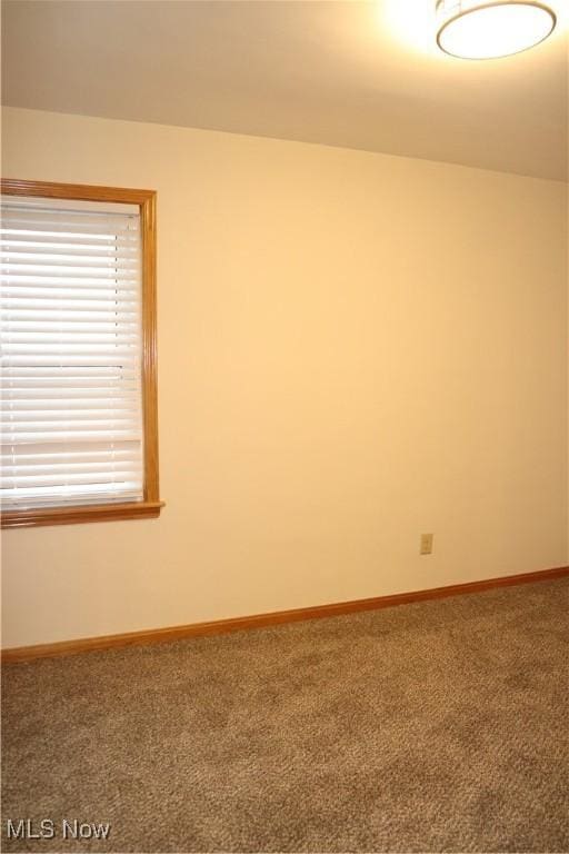 carpeted spare room featuring a wealth of natural light and baseboards