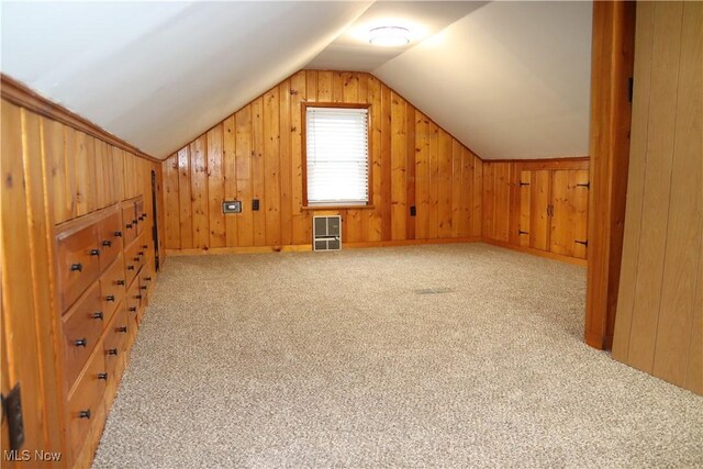 additional living space with lofted ceiling, light carpet, wood walls, and heating unit