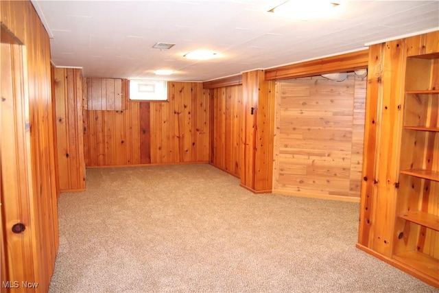 below grade area featuring visible vents, light colored carpet, and wooden walls