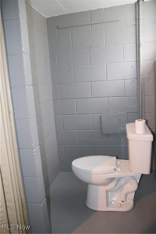 bathroom with concrete block wall and toilet