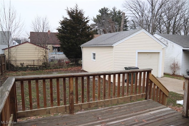 wooden deck featuring concrete driveway, an outdoor structure, and fence