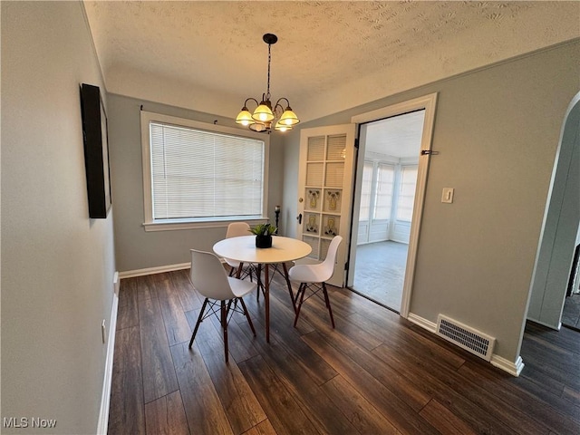 dining space featuring arched walkways, dark wood-style flooring, visible vents, and an inviting chandelier