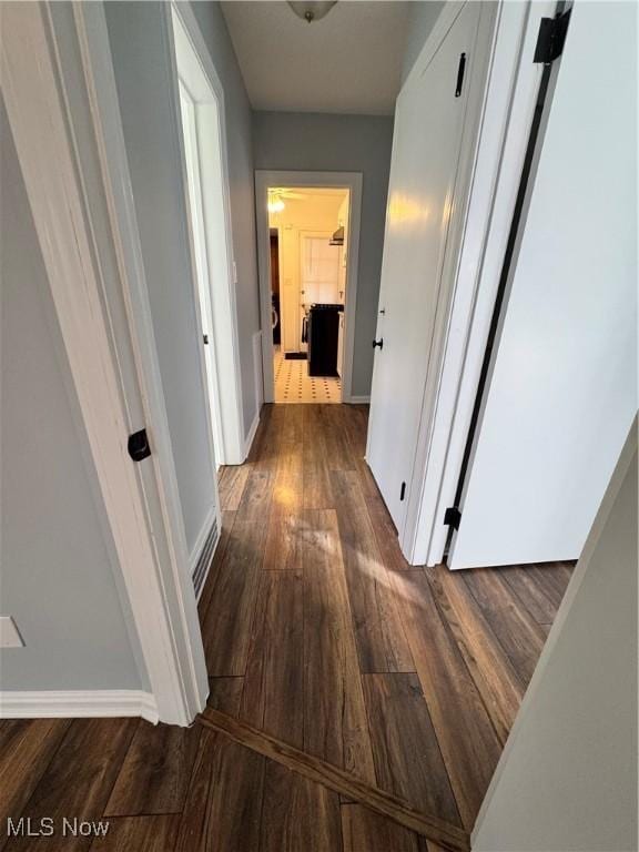 hallway featuring dark wood finished floors and baseboards