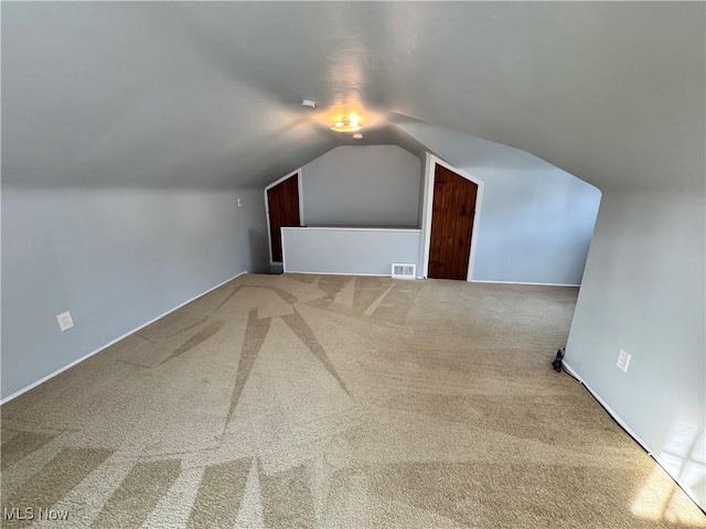 bonus room with carpet floors, visible vents, and vaulted ceiling