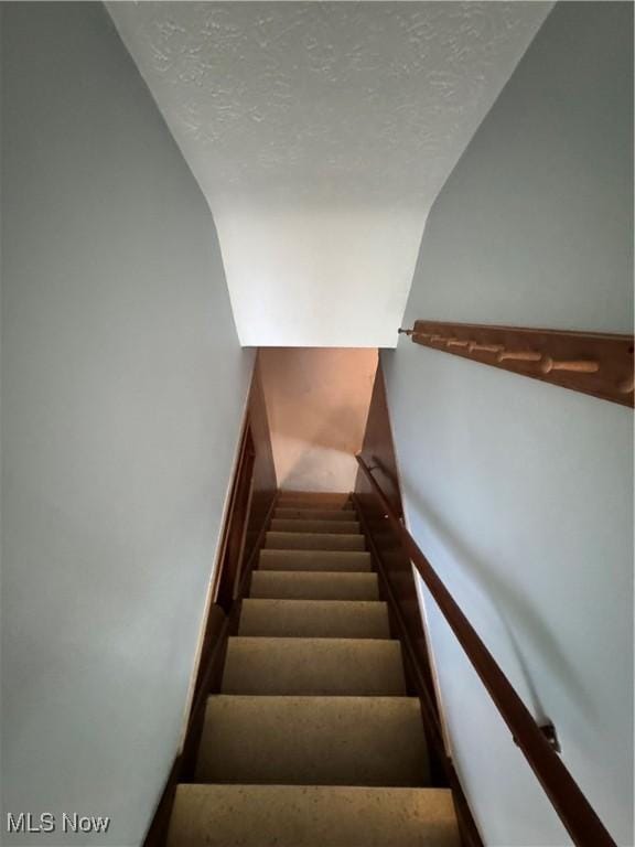 staircase with a textured ceiling