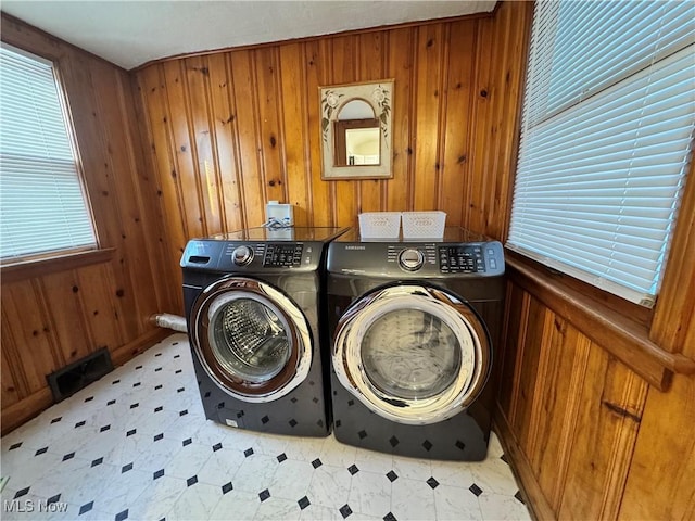 laundry area featuring light floors, wooden walls, visible vents, and washer and dryer