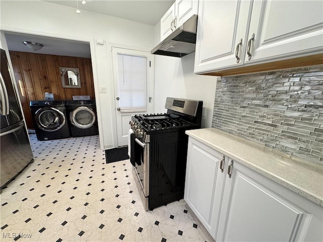 kitchen with washing machine and dryer, under cabinet range hood, white cabinetry, light countertops, and stainless steel range with gas cooktop