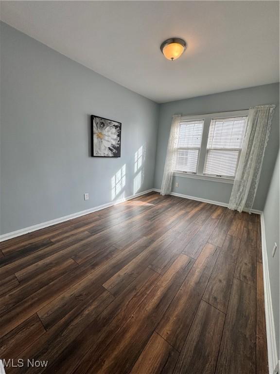 empty room with dark wood-style flooring and baseboards