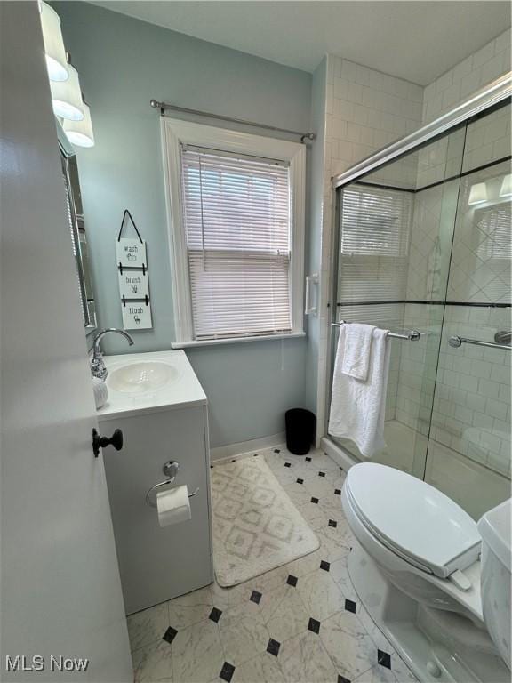 bathroom with toilet, a shower stall, vanity, and baseboards