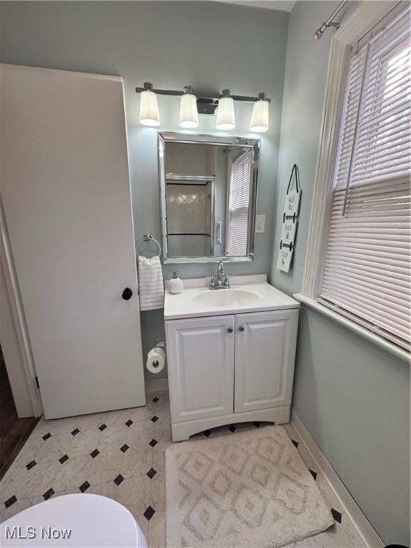 full bath with a shower with shower door, toilet, vanity, and baseboards