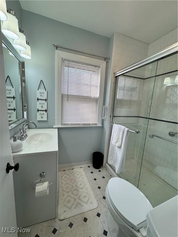 full bathroom with a stall shower, vanity, toilet, and baseboards