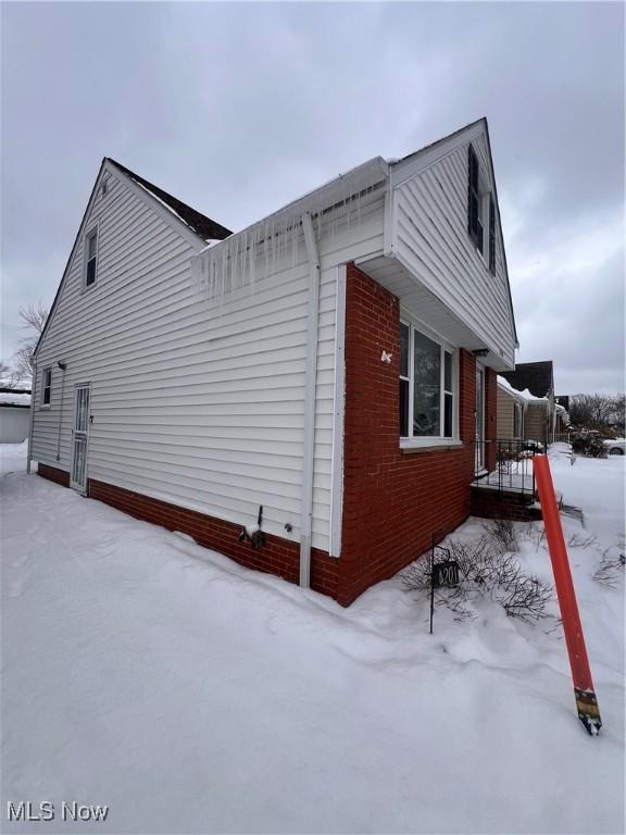 view of snowy exterior featuring brick siding