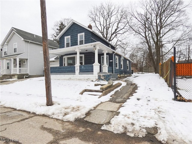 view of front of home featuring a porch, a chimney, and fence