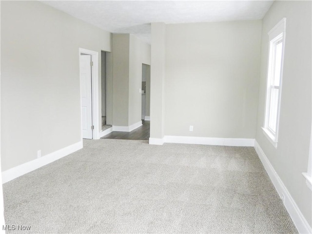 spare room featuring carpet flooring and baseboards