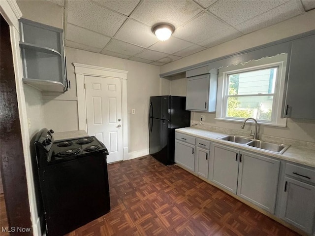 kitchen with light countertops, a sink, black appliances, and open shelves