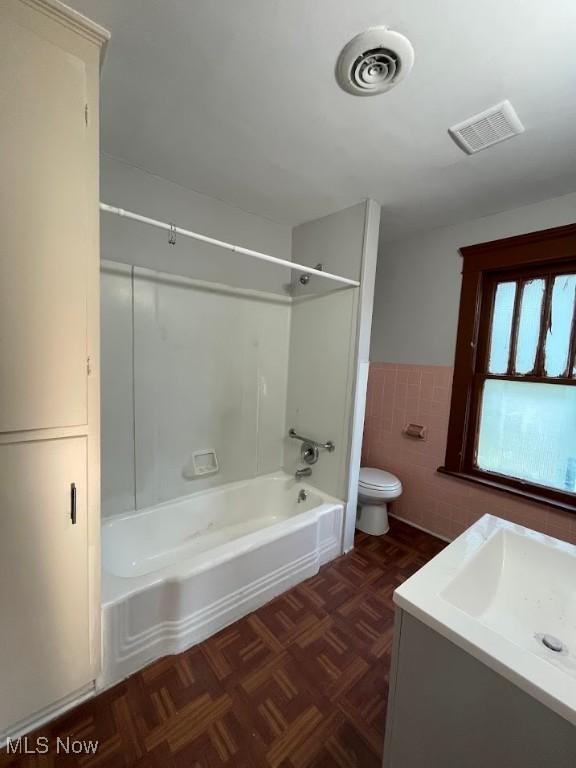 full bathroom featuring wainscoting, visible vents, tile walls, and toilet