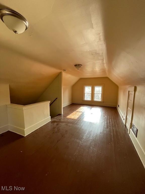 bonus room featuring dark wood-style flooring and vaulted ceiling