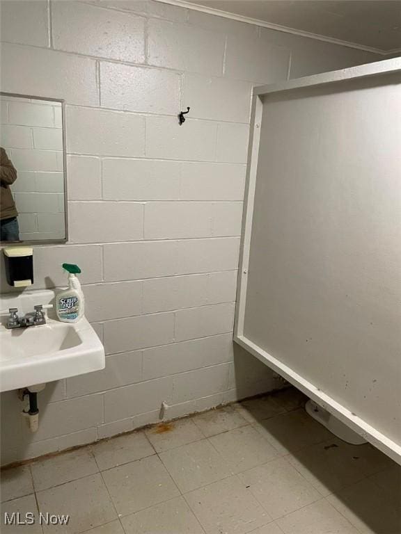 bathroom featuring concrete block wall and a sink