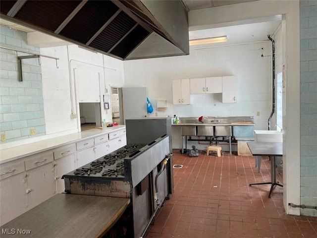 kitchen with range hood, light countertops, white cabinetry, and decorative backsplash