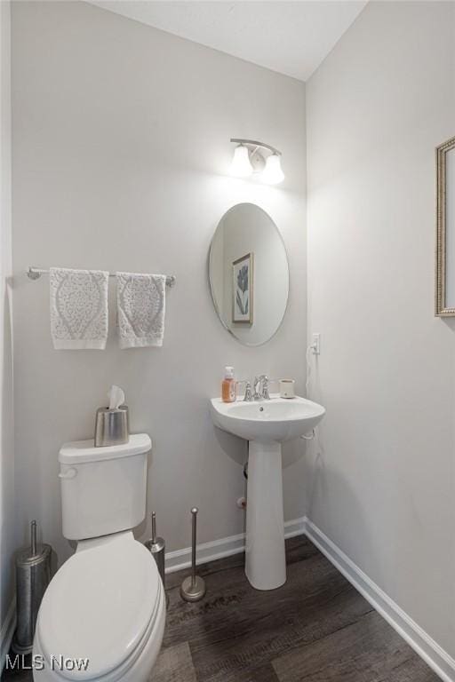 half bathroom featuring toilet, baseboards, and wood finished floors