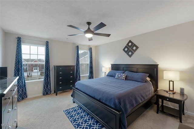 bedroom featuring a ceiling fan, light colored carpet, and baseboards