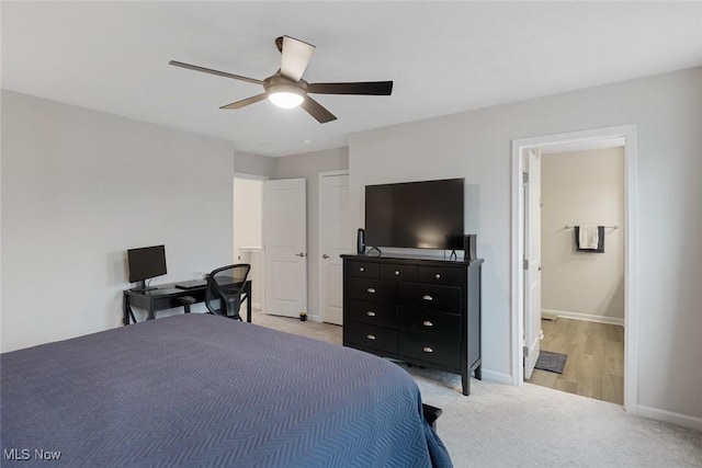 bedroom with light colored carpet, ceiling fan, ensuite bath, and baseboards