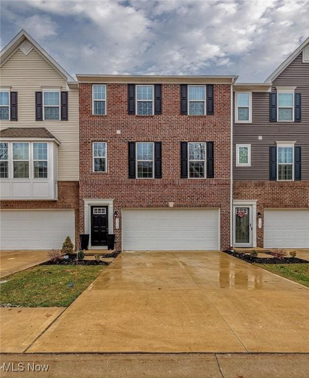 view of property featuring driveway, a garage, and brick siding