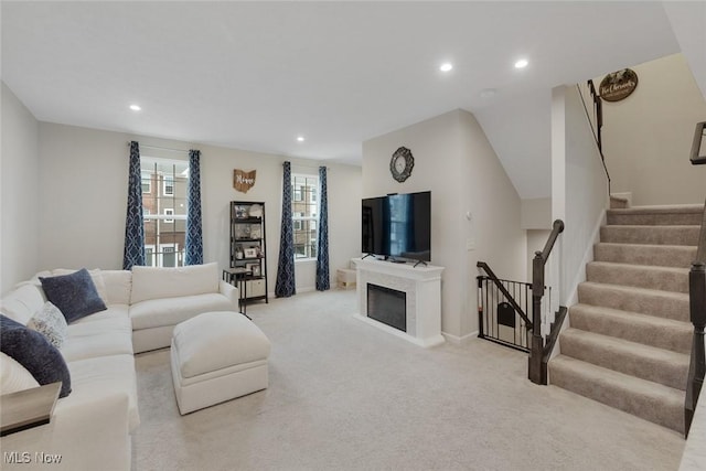 living area featuring recessed lighting, light carpet, a fireplace, and stairway