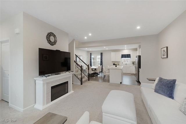 living room featuring a fireplace, recessed lighting, stairway, light carpet, and baseboards