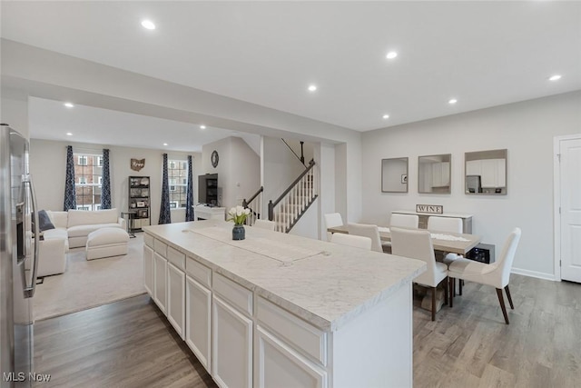 kitchen with light countertops, open floor plan, white cabinetry, a kitchen island, and stainless steel fridge with ice dispenser