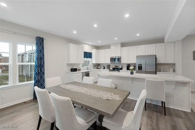 dining area with light wood finished floors, a wealth of natural light, and recessed lighting