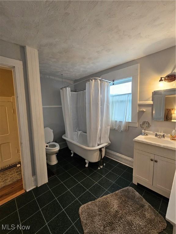 full bath featuring baseboards, toilet, tile patterned flooring, a textured ceiling, and vanity