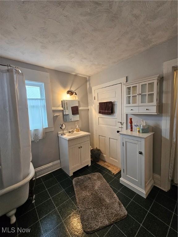 bathroom featuring tile patterned floors, baseboards, a textured ceiling, and vanity