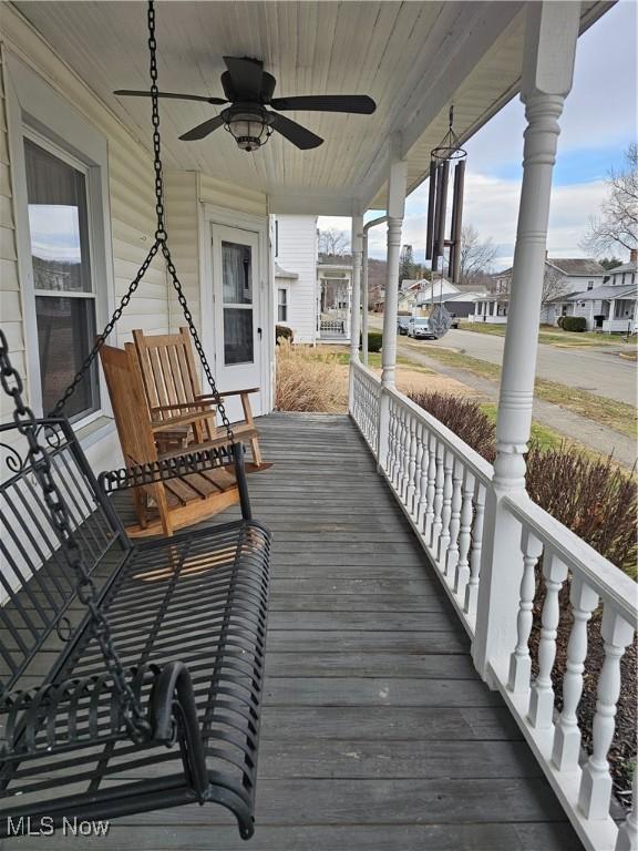 wooden deck with a porch, a residential view, and ceiling fan