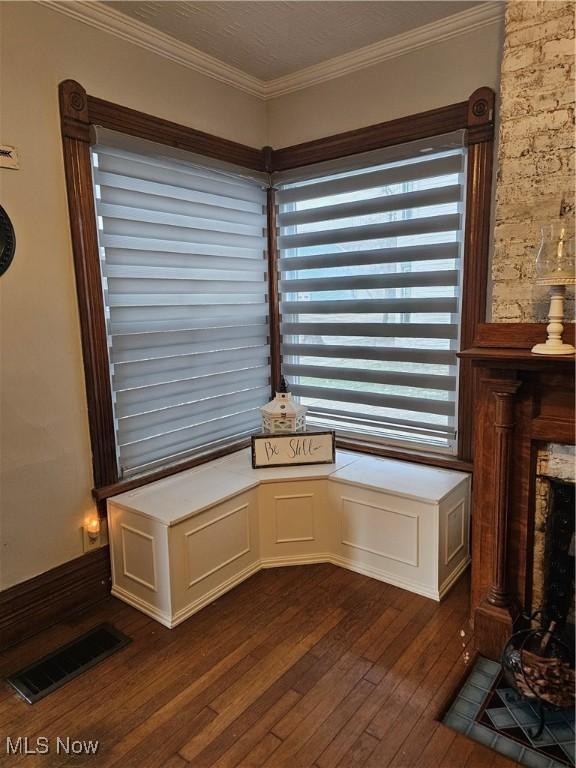 room details with a fireplace with flush hearth, visible vents, wood finished floors, and ornamental molding