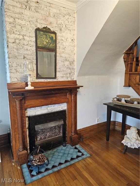 sitting room featuring baseboards, wood finished floors, a fireplace with flush hearth, and crown molding