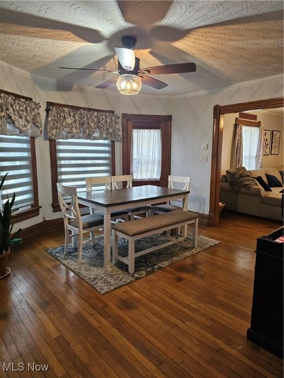 dining room with dark wood-style floors, a wealth of natural light, and crown molding